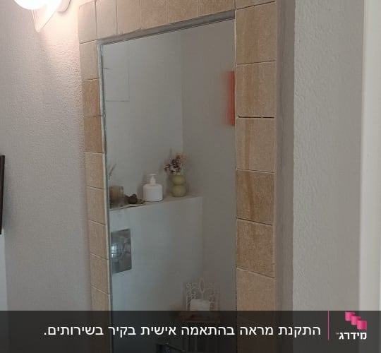 מראה עם מסגרת אריחים וכלי עבודה על כיור